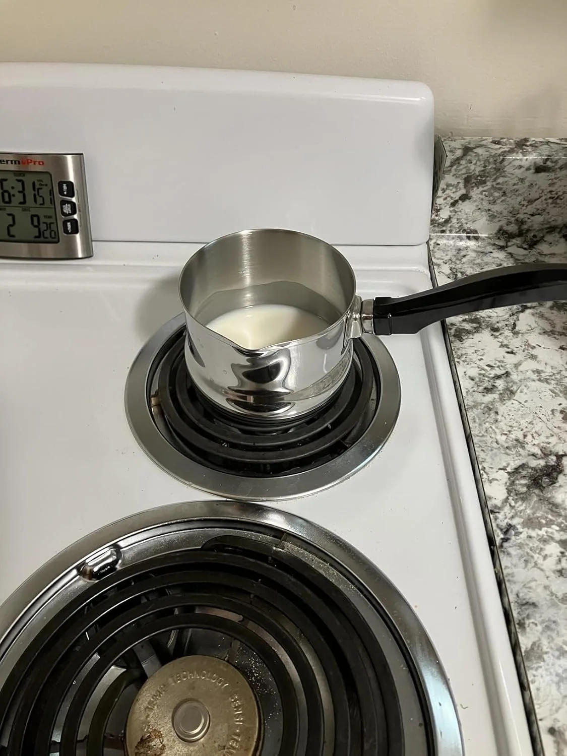 Customer photo of stainless steel double boiler on electric stovetop with milk inside upper pot