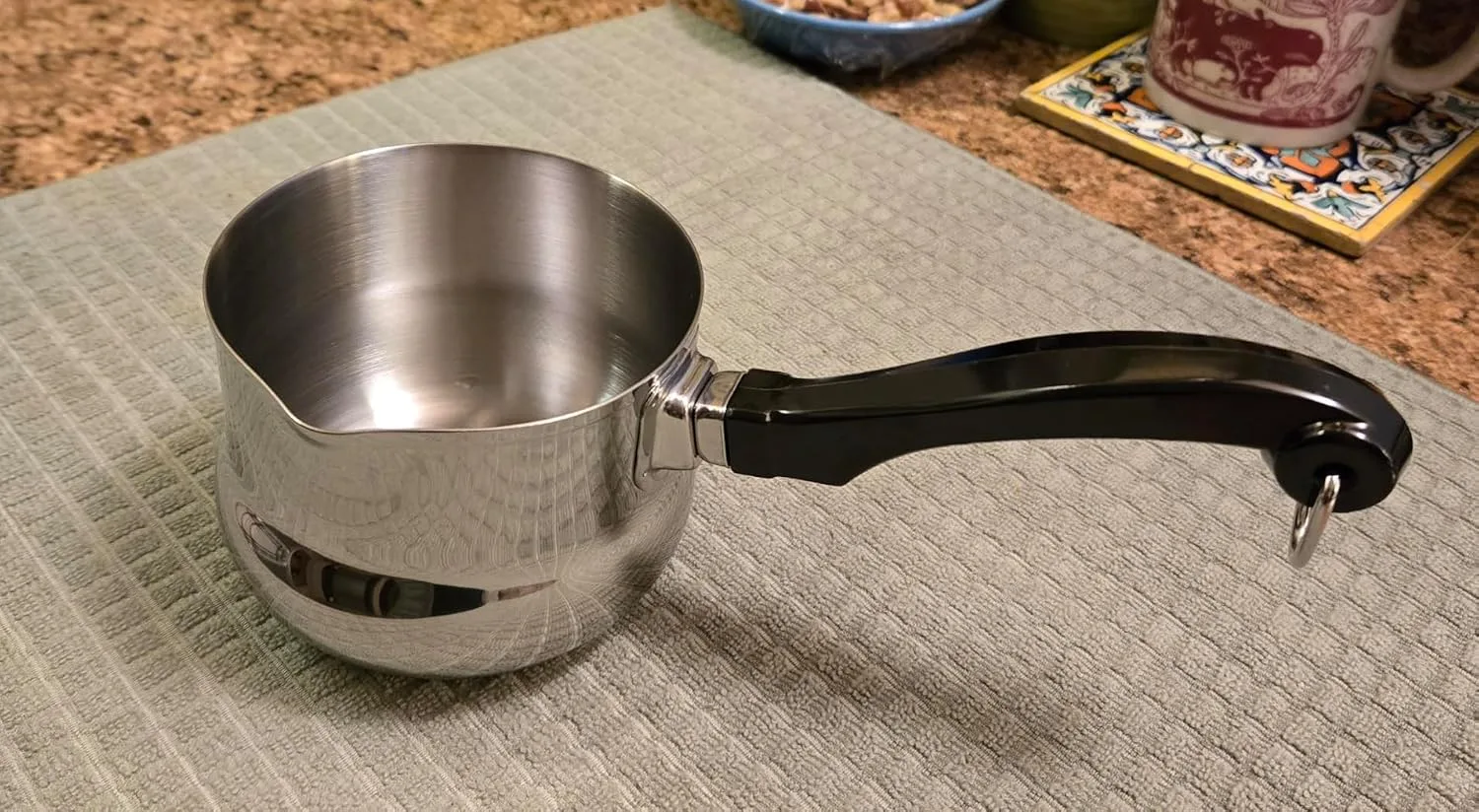 Customer photo of stainless steel double boiler with black handle on beige mat
