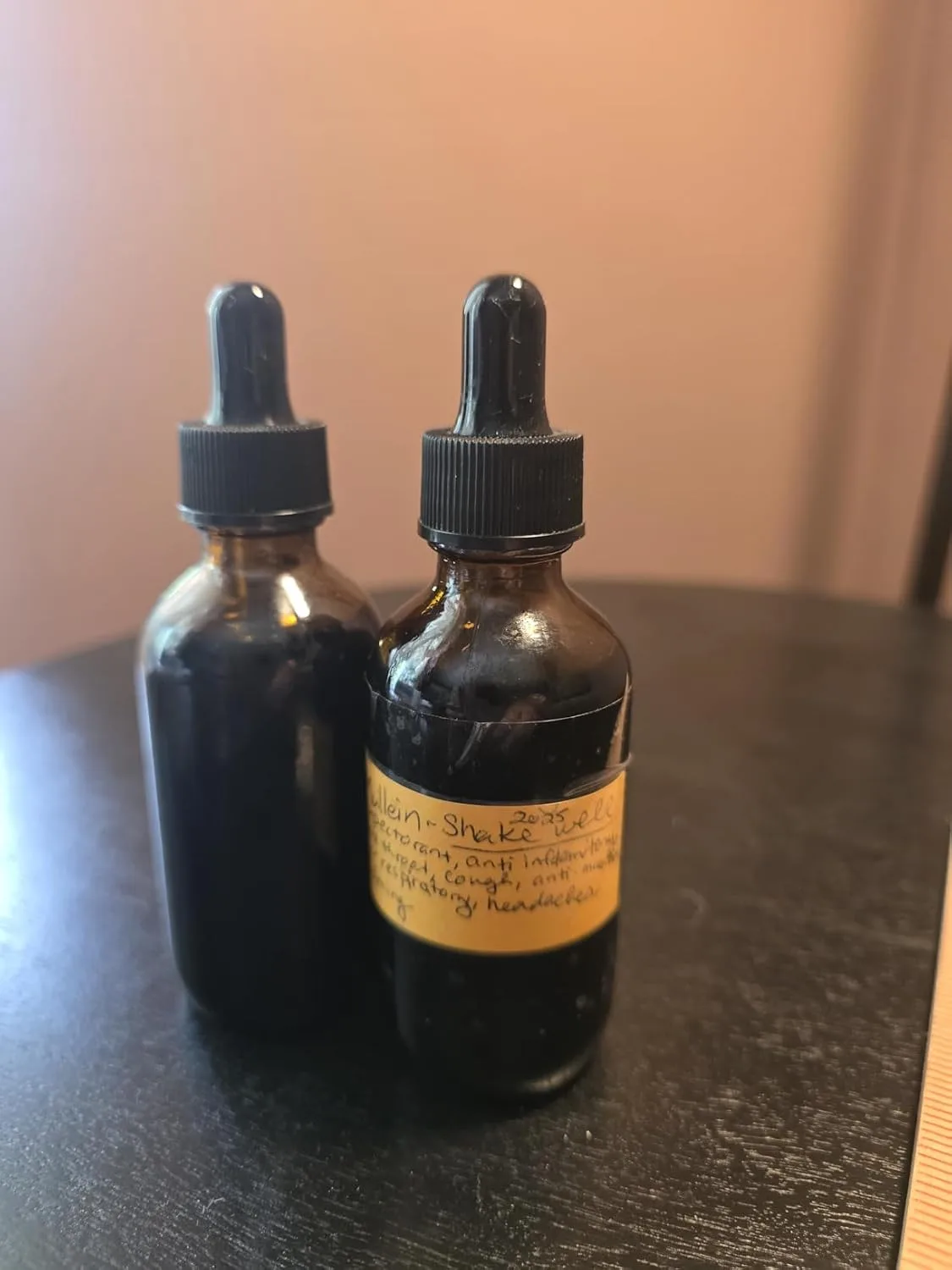Customer photo of two amber glass dropper bottles on a dark surface, one labeled with handwritten text.