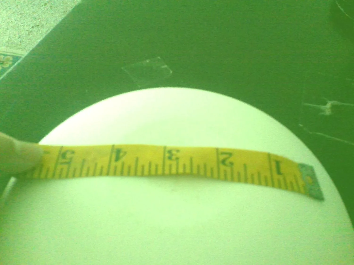 Customer photo of a white ceramic crucible being measured with a yellow tape measure